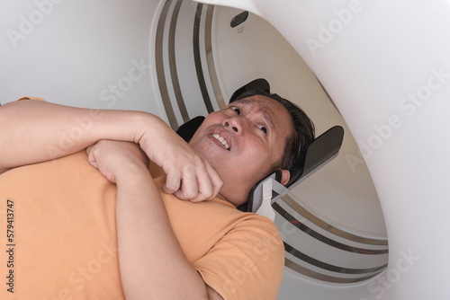 A male patient experiences claustrophobia while going inside the CT scanner machine at the clinic. Fearful of tight spaces.