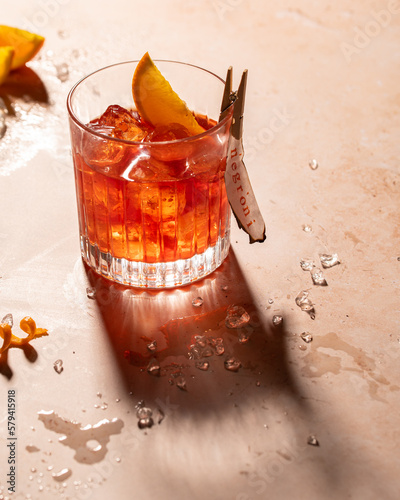 Negroni, an Italian cocktail made of gin, vermouth rosso and Campari with clear ice in an old-fashioned glass with a harsh light. photo