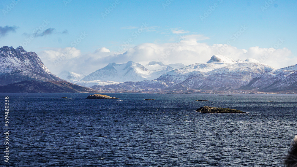 Snow covered Mountains surrounded by fjords in Norway during winter with icy mountain tops