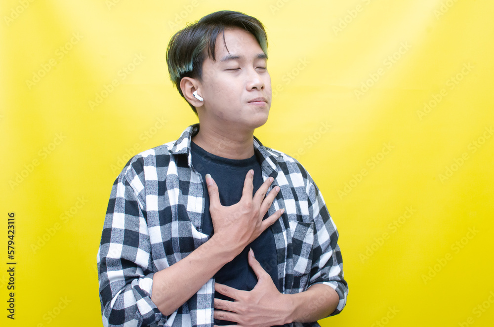 ecstatic Asian man with peek-a-boo hair is happy, enjoying music with AirPods while dancing joyfully and raising fist. ecstatic Asian man with peek-a-boo hair is happy, enjoying music with AirPods while dancing joyfully and raising fist.