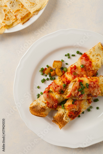 Baked pancakes with chicken in tomato sauce.