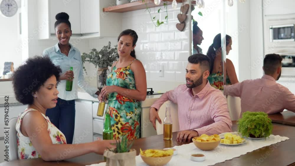 Small party, friends in kitchen talking and laughing. Young adults drinking bier and having fun at home.
