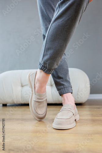 Female legs close-up in gray shoes without heels. Women's comfortable summer casual shoes. Gray women's spring shoes