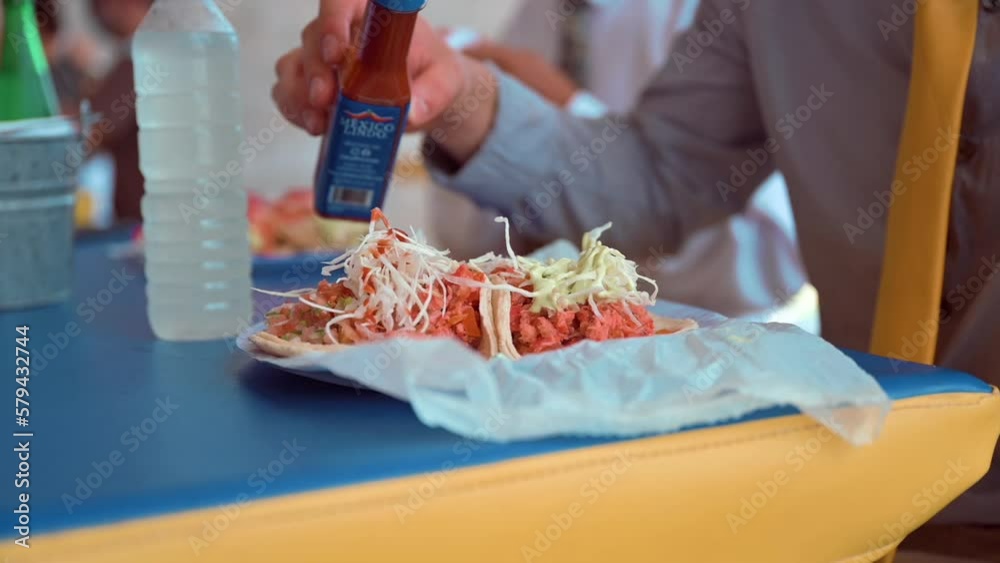 Man pouring hot sauce on his taco