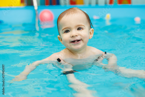 A 2-year-old little boy learns to swim in a pool with a coach. Swimming lessons for children © Дмитрий Ткачук
