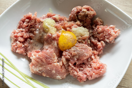 Minced meat, egg, onion and spices in a bowl. Preparing minced cutlets in Poland, traditional Polish kotlety mielone. photo