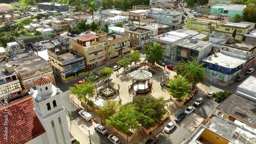 Aerial view of a small town square church and businesses in Barranquitas, Puerto Rico.