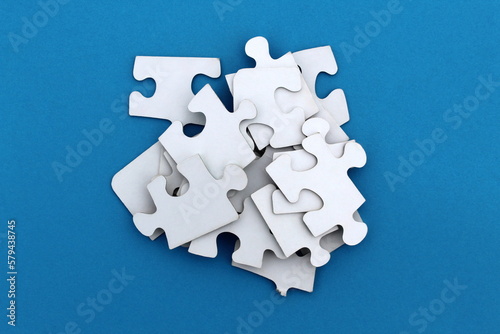 The game, a lot of white puzzle pieces lie on a blue background. 