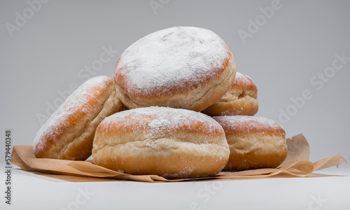 Polish pączki deep-fried doughnuts. Celebrating Fat Thursday, Tłusty czwartek feast, traditional day in Poland. Pączek food, powdered sugar topped and filled with rose hip jam.