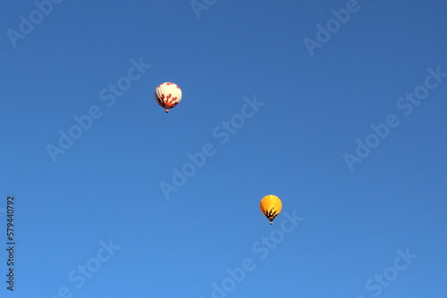 Two hot air balloons are visible against the blue sky.