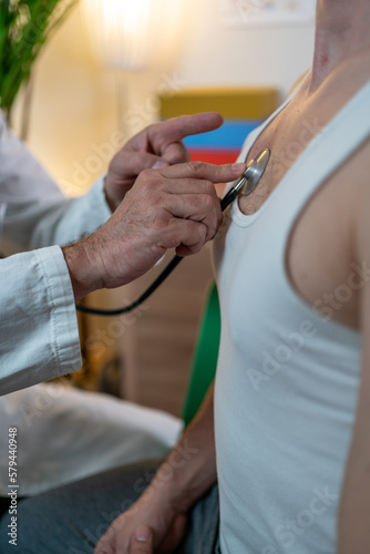 middle-aged doctor using stethoscope to examine patient.