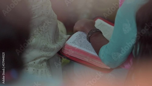 Indian woman holding the Bible with one hand and reading it surrounded by other people photo