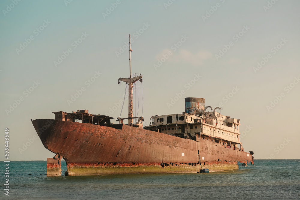 Abandoned old rusty ghost ship (Temple Hall) in 1977 due to a shipwreck near Arrecife, Lanzarote, Spain. Clear sky with sunset Abandoned old rusty ghost ship (Temple Hall) in 1977 due to a shipwreck near Arrecife, Lanzarote, Spain. Clear sky with sunset