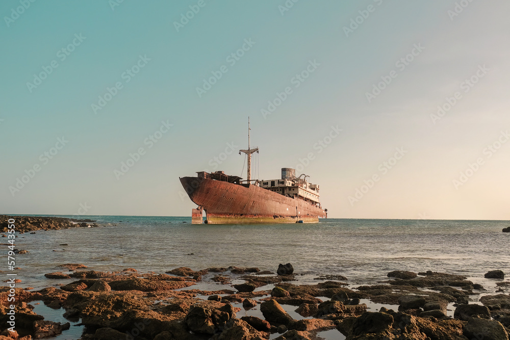 Abandoned old rusty ghost ship (Temple Hall) in 1977 due to a shipwreck near Arrecife, Lanzarote, Spain. Clear sky with sunset