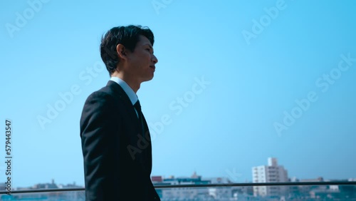 青空の下を颯爽と歩く日本人ビジネスマン, A Japanese businessman walking briskly under a blue sky, 4K video