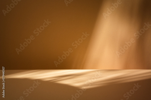 Fototapeta Naklejka Na Ścianę i Meble -  Empty wooden table on brown background with natural shadow on the wall. Mock up for branding products, presentation, food and health care.	

