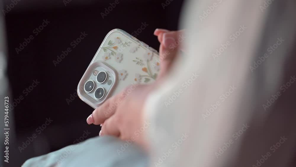 Closeup of a female holding a phone in her hands with a beautiful floral case