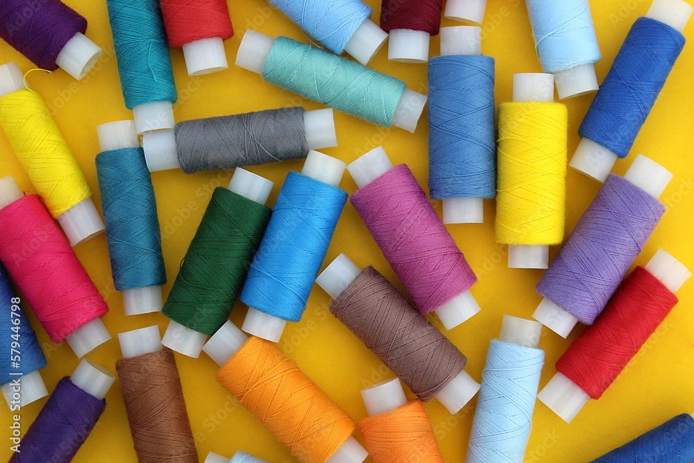 Background of multi-colored bright threads lying on a yellow background.
Background of multi-colored bright threads lying on a yellow background.