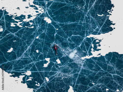 Obraz na płótnie aerial view of a man with beard in sweater and in ice skates lying on blue ice of abraham lake in jasper and banff national park w salonie