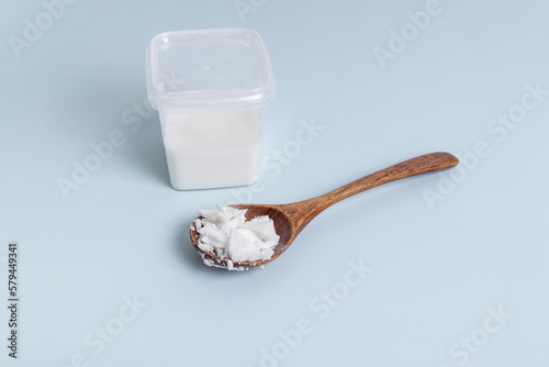 Soy or coconut wax in plastic container and wooden spoon. Wax for making candles