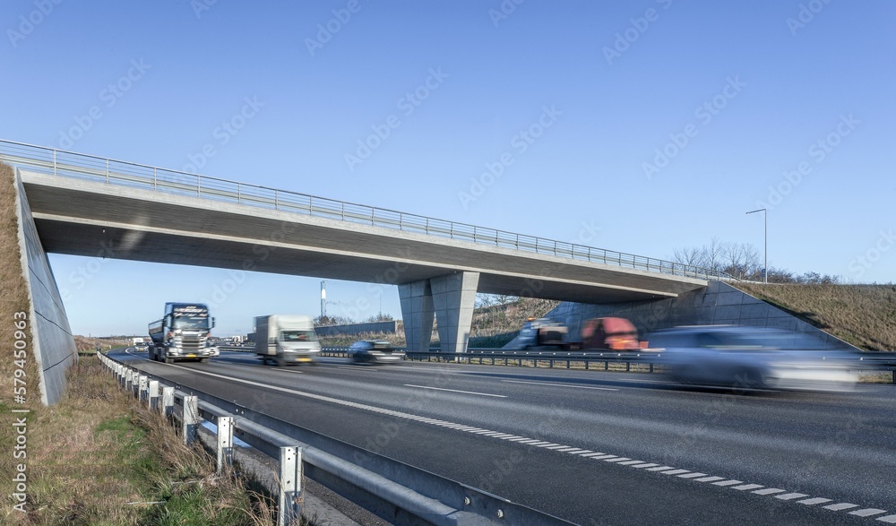 Long highway with passing cars under a blue sky in Denmark