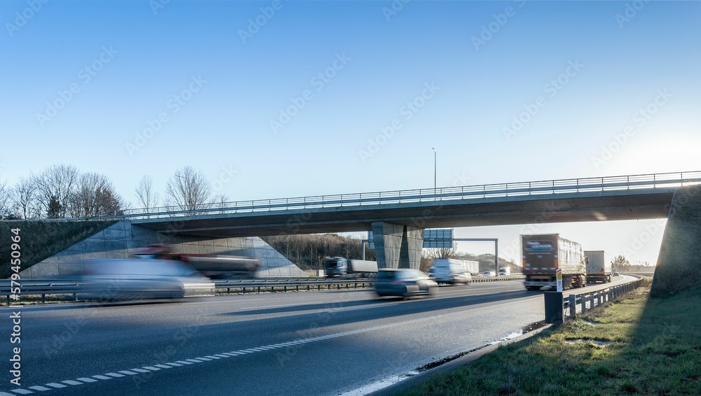 Long highway with passing cars under a blue sky in Denmark