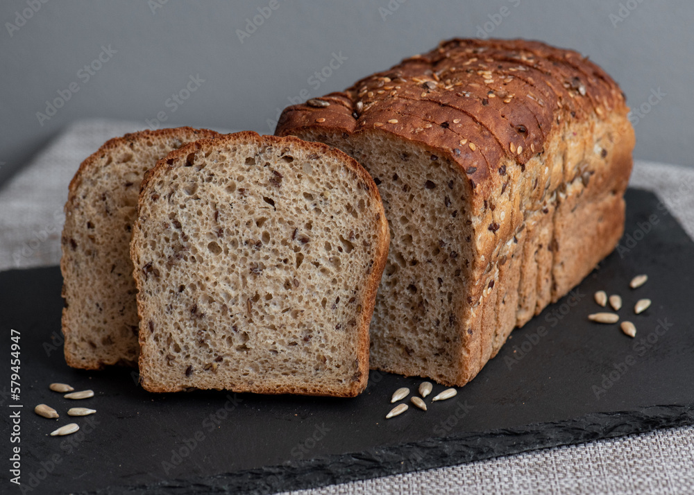 Rye bread with seeds lies on a dark board on a light table. My home