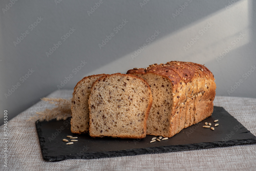 Rye bread with seeds lies on a dark board on a light table. My home