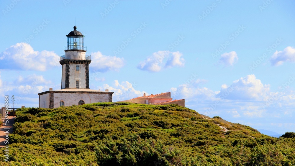 a lighthouse on the top of a hill surrounded by greene
