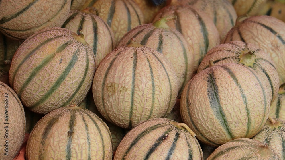 several whole melons on display at the market stall,