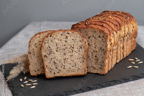 Rye bread with seeds lies on a dark board on a light table. My home bakery. Organic whole grain bread. Bio Dinkel Brot. Healthy bread. complex carbohydrates. health diet. Healthy breakfast.