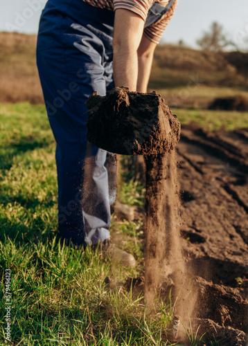 Earth on a shovel. The gardener digs the soil with a shovel in the garden in spring, black soil on the farm.