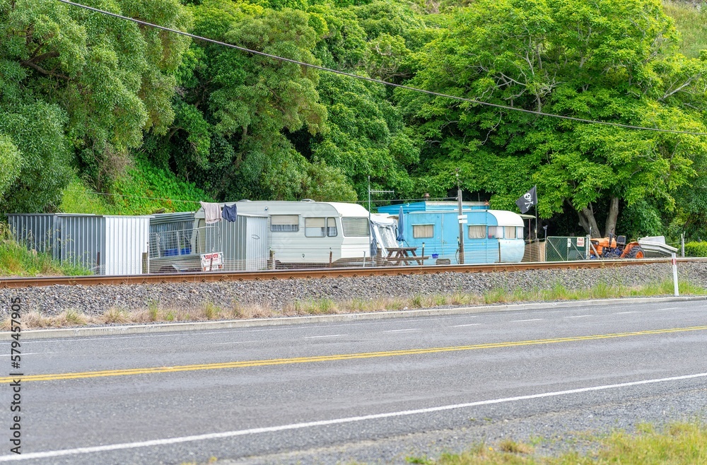 Row of camper vans parked at a campsite by the road and railway in New Zealand