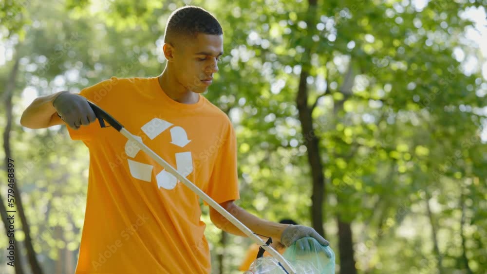 Side View of Multiethnic Young Man Using Trash Picker While Collecting