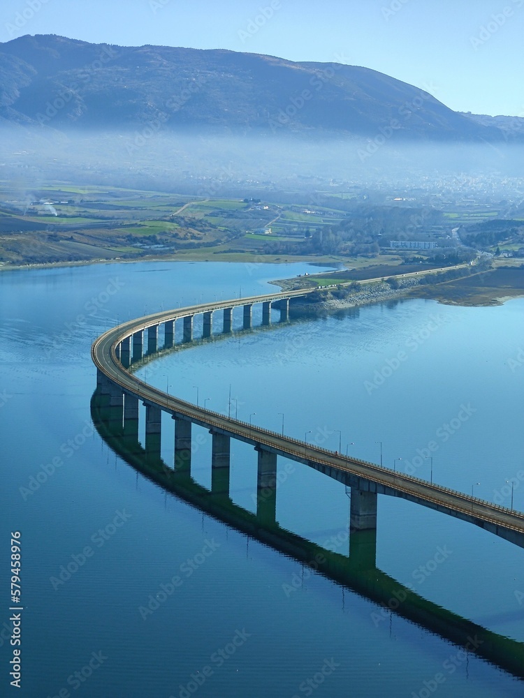 Vertical aerial view of the Lake Polyfytos Bridge with a blue sky in the background, Greece Vertical aerial view of the Lake Polyfytos Bridge with a blue sky in the background, Greece
