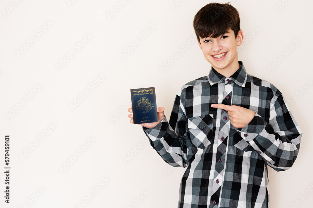Young teenager boy holding Bhutan passport looking positive and happy standing and smiling with a confident smile against white background. Young teenager boy holding Bhutan passport looking positive and happy standing and smiling with a confident smile against white background.