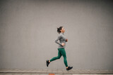 Full length of a fit female runner running on the street.