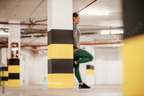 A sportswoman is taking a break after exercising in underground garage.