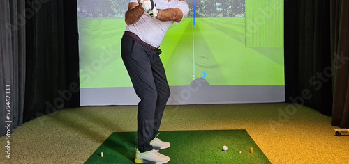 Quadro su tela Professional male golfer holding club playing golf indoors on golf simulator