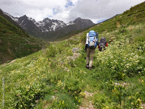 Backpacker nature walkers walking through yellow flowers in Kaçkar Mountains