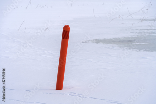 Fotografie Red navigational spar buoy on a frozen lake