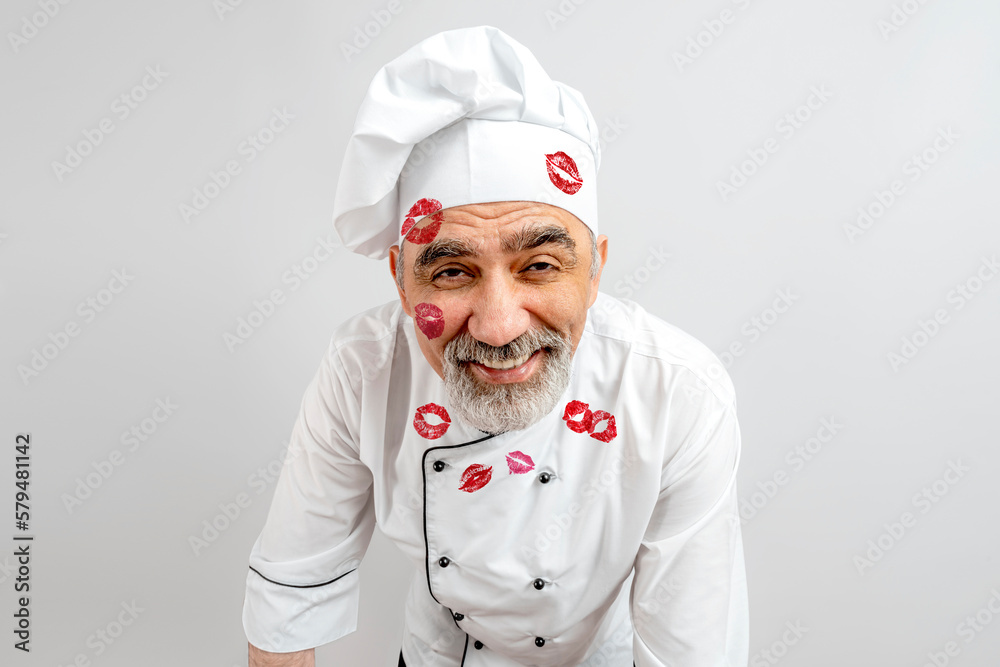 Chef-cooker in a chef's hat and jacket with lipstick marks on face skin and  clothes. Senior professional baker man wearing a chef's outfit. Character  kitchener, pastry chef for advertising Stock Photo