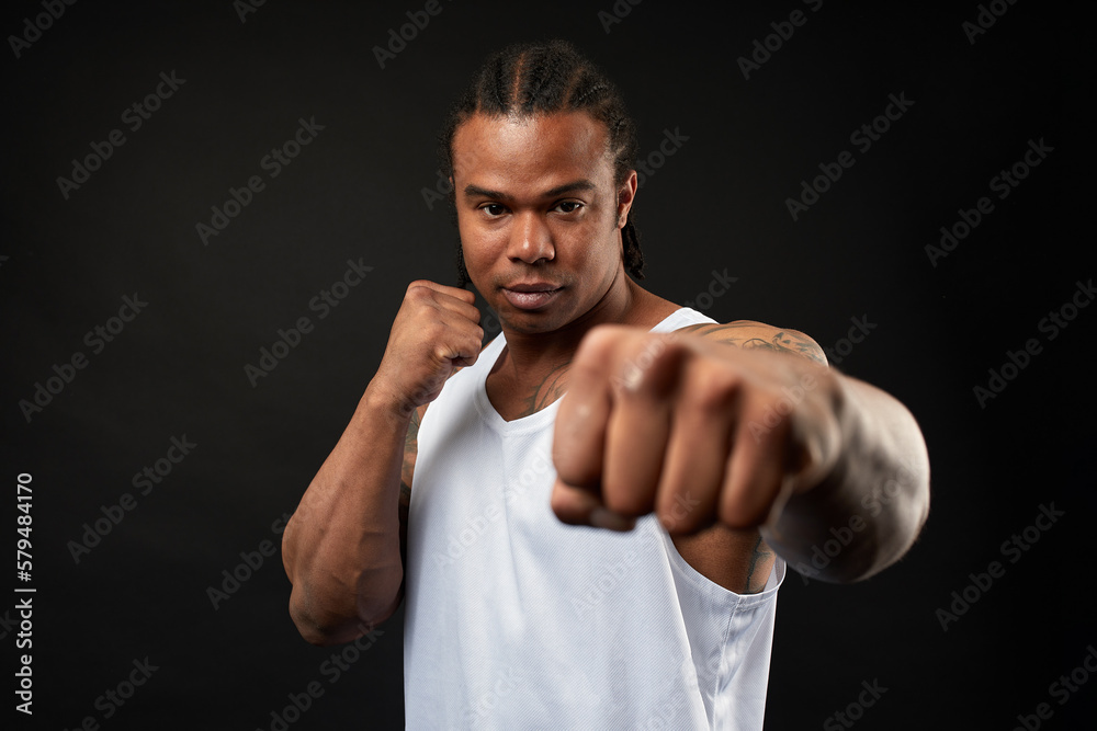 portrait of African-American athlete man boxing on black background