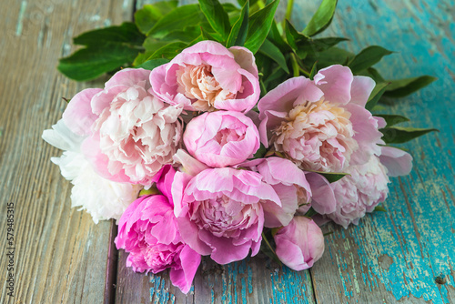 Greeting card with peonies on the old blue paint wooden background © stsvirkun