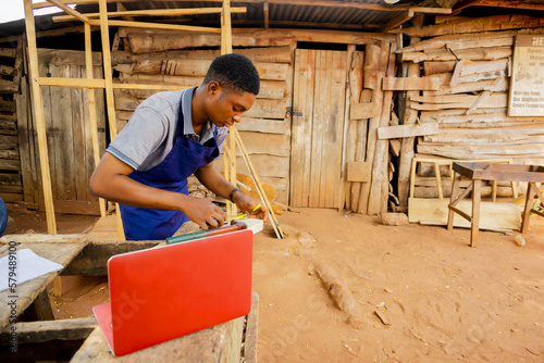 young african carpenter standing holding working calling laptop