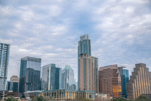 Austin, Texas cityscape against the cloudy sky background. Facade of residential and business skyscrapers with reflective glass exterior.