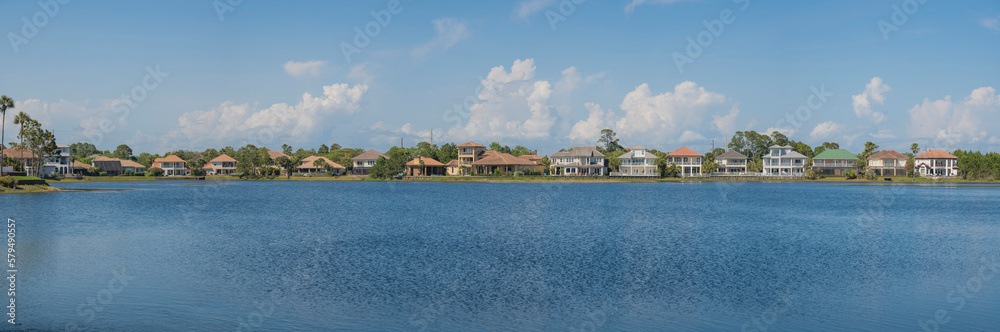 Panorama of Four Prong Lake surrounded by residential houses at Destin, Florida. Waterfront houses against the puffy clouds in the blue sky background.