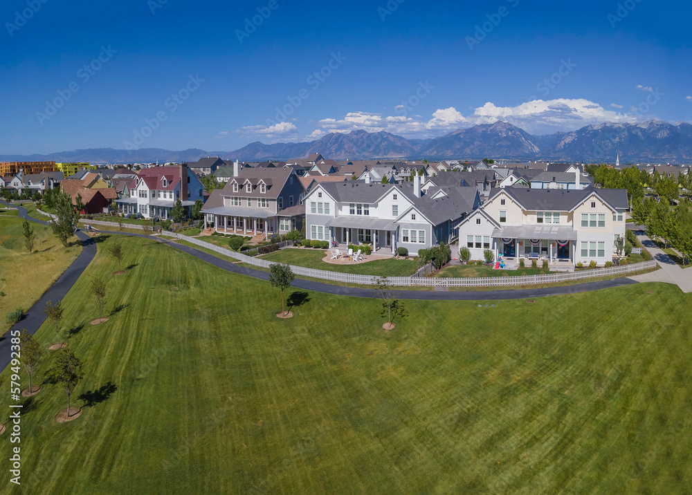 Lovely homes in beautiful Daybreak Utah amid lush green field and mountains. Aerial view of a serene neighborhood landscape surrounded by an nature scenery.