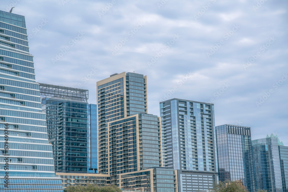 View of modern buildings with glass exterior from Auditorium Shores Park- Austin, Texas. Cityscape view near Colorado River against the cloudy sky background.