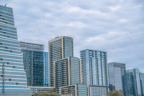 View of modern buildings with glass exterior from Auditorium Shores Park- Austin  Texas. Cityscape view near Colorado River against the cloudy sky background.